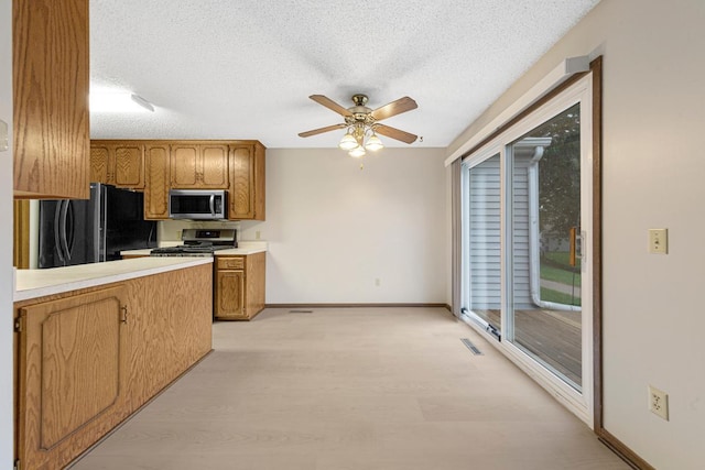 5214 148th St W, Apple Valley, MN 55124 - kitchen with stainless steel appliances, ceiling fan, light wood-style floors, a textured ceiling, and brown cabinetry