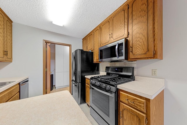 5214 148th St W, Apple Valley, MN 55124 - kitchen featuring appliances with stainless steel finishes, light countertops, a textured ceiling, and brown cabinetry