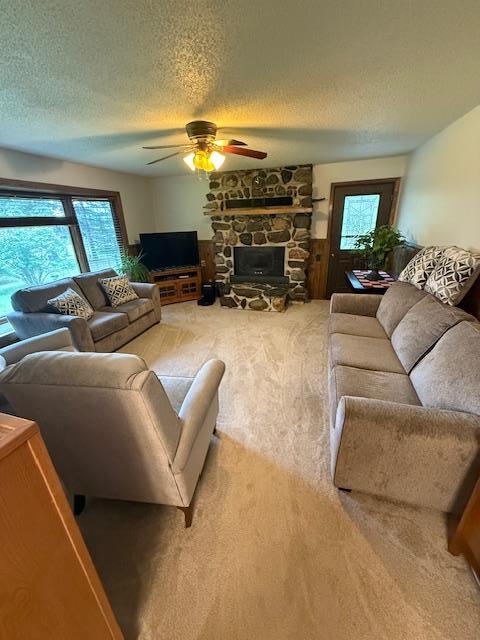 20501 Nebish Rd NE, Blackduck, MN 56630 - living room featuring carpet floors, a ceiling fan, a textured ceiling, and a stone fireplace