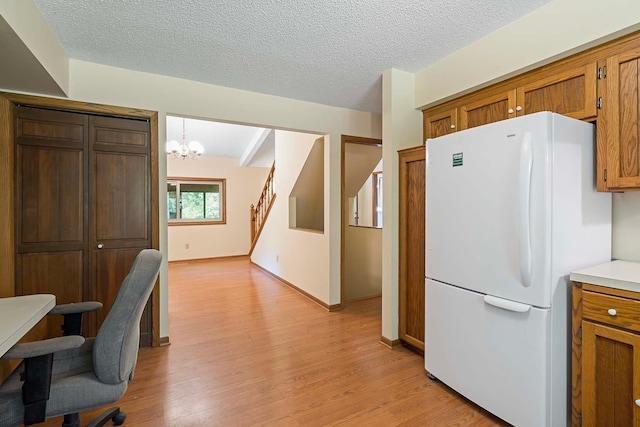 11606 235th St E, Lakeville, MN 55044 - kitchen featuring freestanding refrigerator, light wood-style floors, brown cabinetry, a chandelier, and a textured ceiling