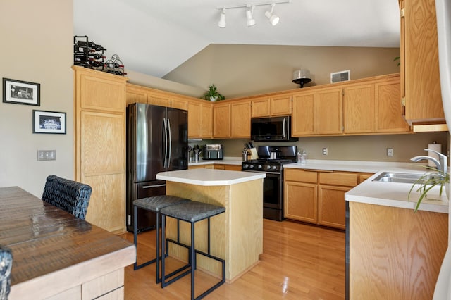 6449 151st St N, Hugo, MN 55038 - kitchen with black appliances, a sink, lofted ceiling, a kitchen bar, and a center island