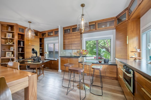 2311 Swan Dr, Mendota Heights, MN 55120 - kitchen with brown cabinetry, open shelves, decorative light fixtures, light wood finished floors, and an office area
