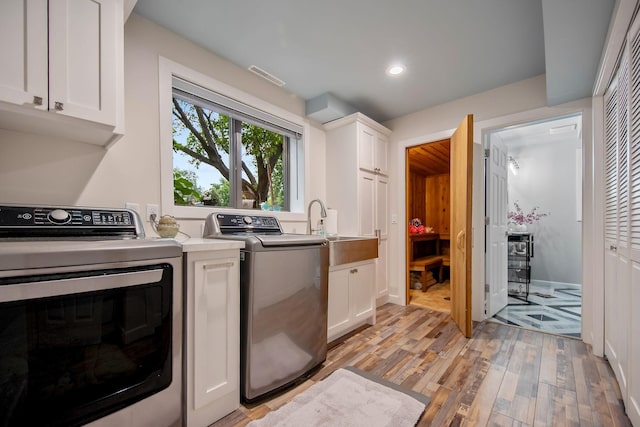 2311 Swan Dr, Mendota Heights, MN 55120 - washroom with cabinet space, light wood finished floors, recessed lighting, and washing machine and dryer