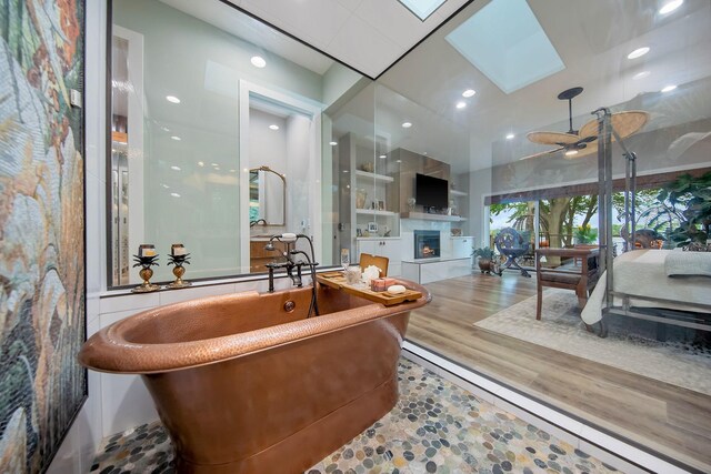 2311 Swan Dr, Mendota Heights, MN 55120 - full bath featuring a skylight, a soaking tub, a tiled fireplace, and a ceiling fan