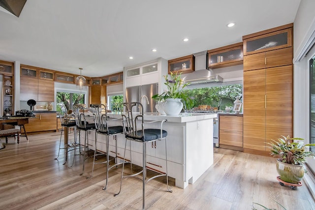 2311 Swan Dr, Mendota Heights, MN 55120 - kitchen with appliances with stainless steel finishes, wall chimney range hood, a center island with sink, a kitchen breakfast bar, and recessed lighting