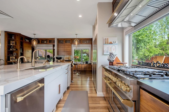 2311 Swan Dr, Mendota Heights, MN 55120 - kitchen featuring wall chimney range hood, appliances with stainless steel finishes, a sink, white cabinets, and light wood-style flooring