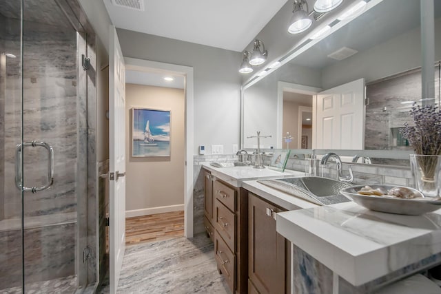 2311 Swan Dr, Mendota Heights, MN 55120 - full bathroom featuring double vanity, a stall shower, wood finished floors, and baseboards