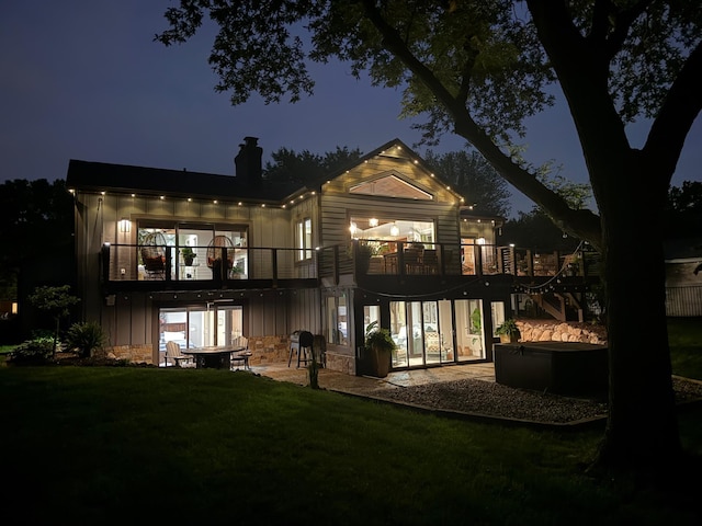 2311 Swan Dr, Mendota Heights, MN 55120 - back of house at twilight featuring a chimney, a patio area, a balcony, a yard, and a hot tub