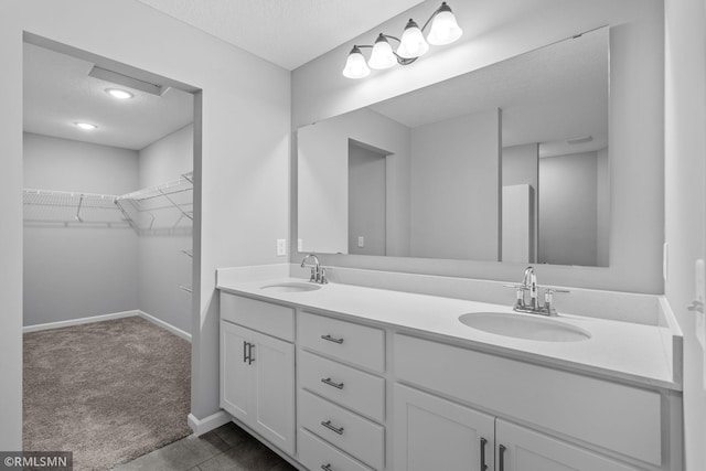 6785 104th St S, Cottage Grove, MN 55016 - bathroom featuring double vanity, a textured ceiling, baseboards, and a walk in closet