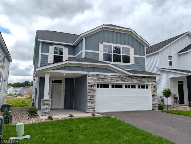 6785 104th St S, Cottage Grove, MN 55016 - view of front of house featuring a garage, board and batten siding, stone siding, asphalt driveway, and a shingled roof