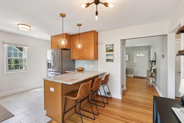 6233 4th Ave S, Richfield, MN 55423 - kitchen featuring stainless steel fridge, brown cabinetry, light wood-type flooring, and a breakfast bar