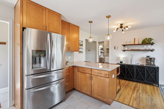 6233 4th Ave S, Richfield, MN 55423 - kitchen with stainless steel fridge with ice dispenser, a peninsula, open shelves, light stone countertops, and brown cabinets
