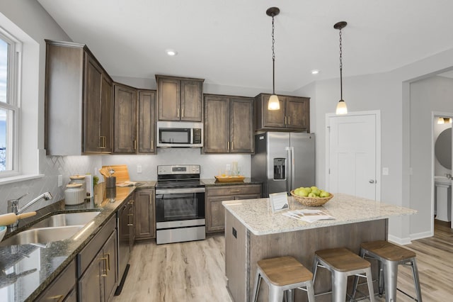 10647 29th St NE, Saint Michael, MN 55376 - kitchen featuring appliances with stainless steel finishes, a sink, light wood-style floors, a kitchen bar, and backsplash