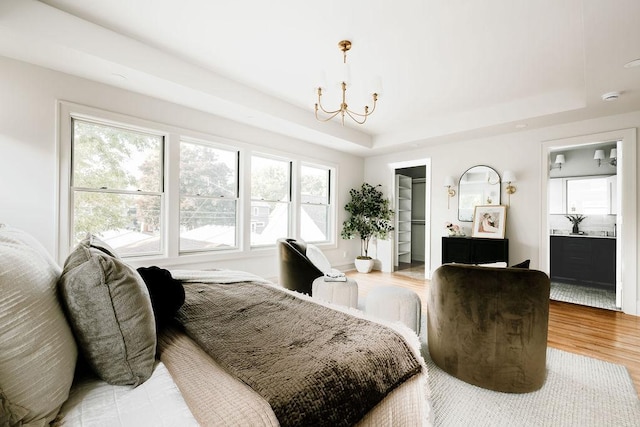 2137 Wellesley Ave, Saint Paul, MN 55105 - bedroom featuring a raised ceiling, a chandelier, light wood finished floors, and a walk in closet