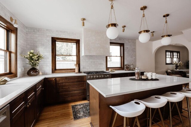 2137 Wellesley Ave, Saint Paul, MN 55105 - kitchen with appliances with stainless steel finishes, wall chimney range hood, a breakfast bar, arched walkways, and healthy amount of natural light