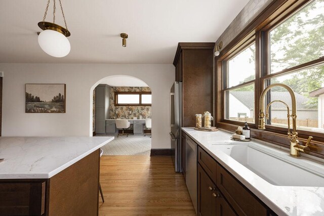 2137 Wellesley Ave, Saint Paul, MN 55105 - kitchen featuring arched walkways, light wood-style floors, dark brown cabinetry, appliances with stainless steel finishes, and light stone countertops