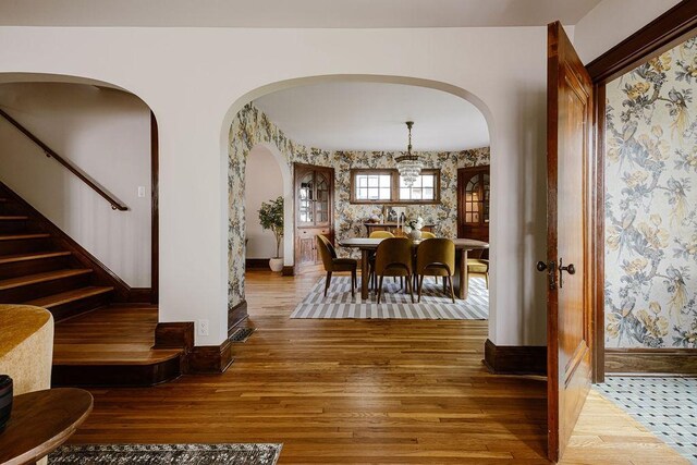 2137 Wellesley Ave, Saint Paul, MN 55105 - dining space featuring arched walkways, wallpapered walls, wood finished floors, and stairs