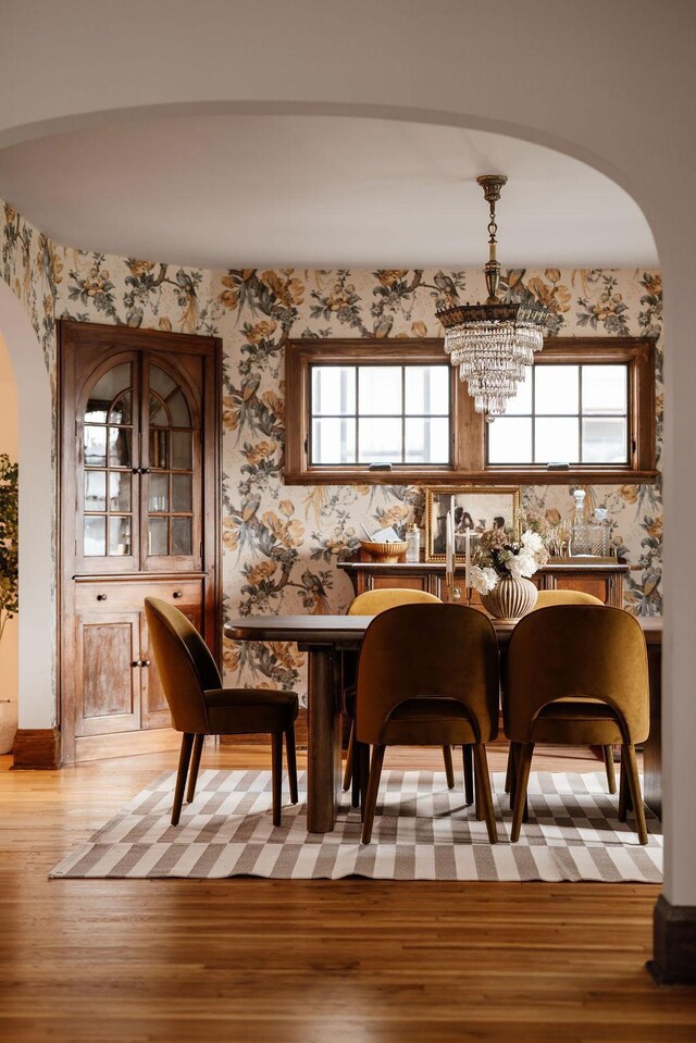 2137 Wellesley Ave, Saint Paul, MN 55105 - dining space featuring arched walkways, light wood finished floors, a chandelier, plenty of natural light, and wallpapered walls