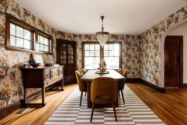 2137 Wellesley Ave, Saint Paul, MN 55105 - dining space featuring light wood-type flooring, healthy amount of natural light, arched walkways, wallpapered walls, and a chandelier