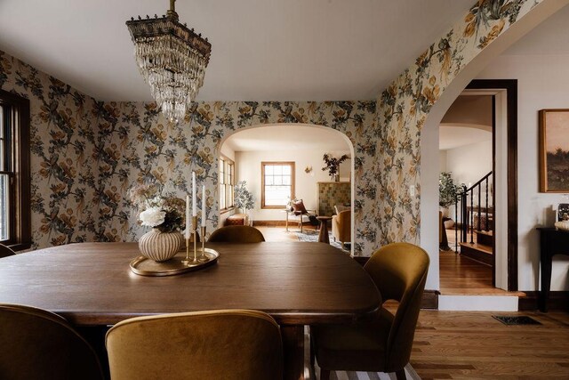 2137 Wellesley Ave, Saint Paul, MN 55105 - dining area with arched walkways, wallpapered walls, wood finished floors, a chandelier, and stairs