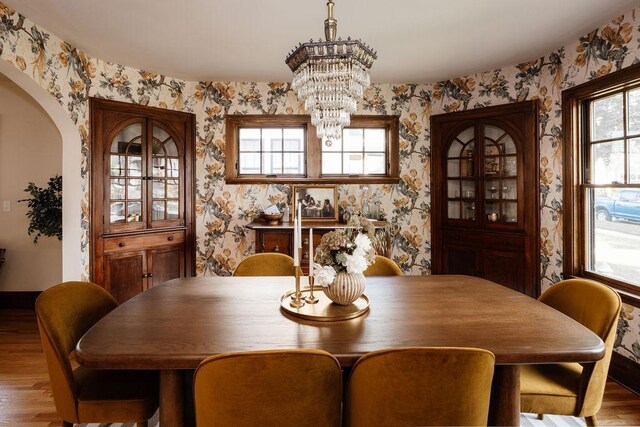 2137 Wellesley Ave, Saint Paul, MN 55105 - dining space with wood finished floors, wallpapered walls, a chandelier, and arched walkways