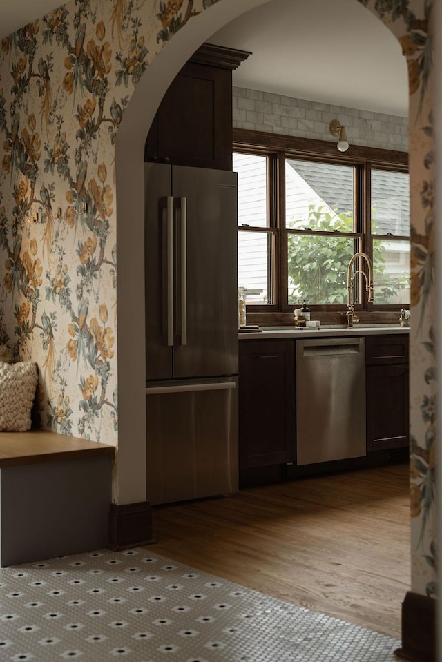 2137 Wellesley Ave, Saint Paul, MN 55105 - kitchen featuring appliances with stainless steel finishes, wallpapered walls, arched walkways, light wood-style flooring, and light countertops