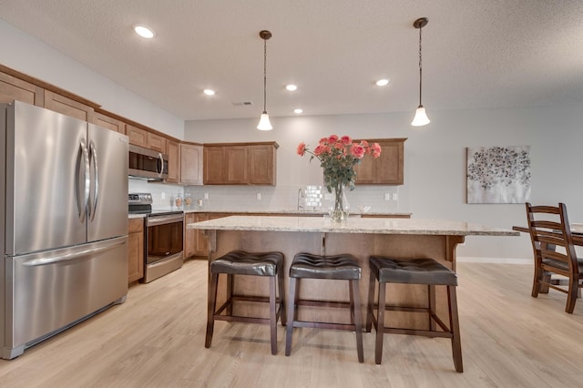 2605 Hanson Ave, Faribault, MN 55021 - kitchen featuring stainless steel appliances, light wood finished floors, decorative backsplash, a breakfast bar area, and recessed lighting