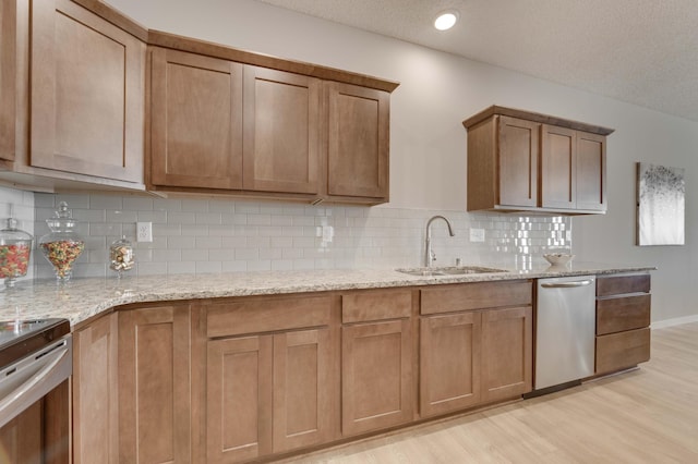 2605 Hanson Ave, Faribault, MN 55021 - kitchen with a sink, appliances with stainless steel finishes, light wood-style flooring, light stone counters, and backsplash