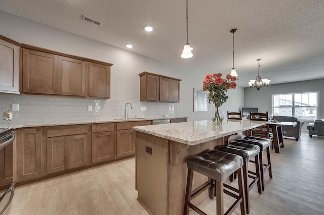 2605 Hanson Ave, Faribault, MN 55021 - kitchen featuring a sink, light wood-style floors, a textured ceiling, brown cabinetry, and recessed lighting