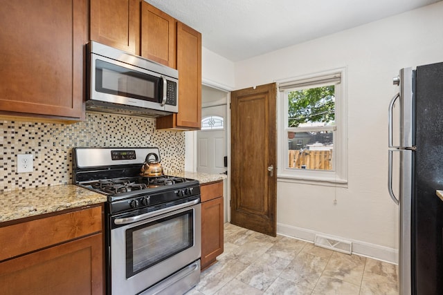 4545 5th Ave S, Minneapolis, MN 55419 - kitchen featuring stainless steel appliances, decorative backsplash, brown cabinets, and light stone countertops