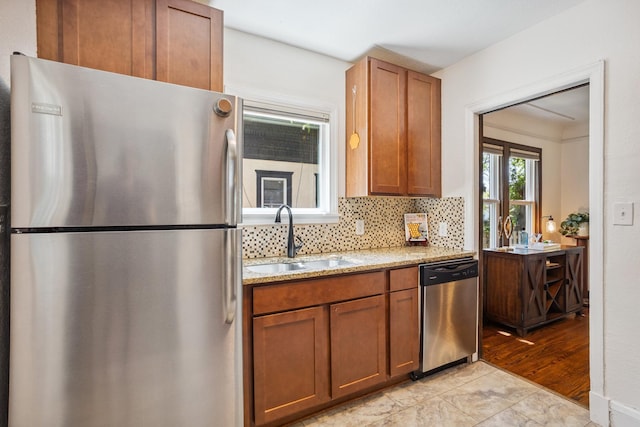 4545 5th Ave S, Minneapolis, MN 55419 - kitchen featuring stainless steel appliances, decorative backsplash, light stone countertops, brown cabinets, and light wood-style floors
