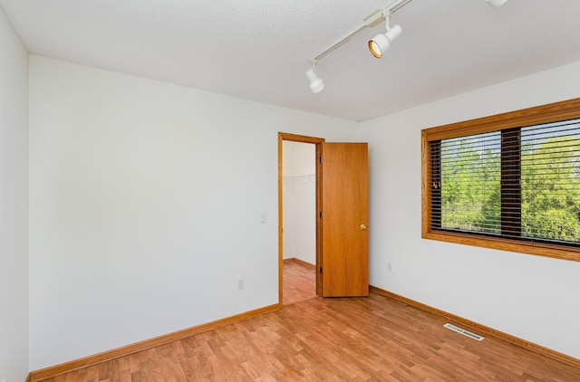 6122 152nd St N, Hugo, MN 55038 - empty room featuring light wood-style flooring, baseboards, and rail lighting