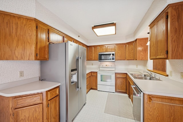 2639 Lake Court Cir Unit 81, Mounds View, MN 55112 - kitchen featuring appliances with stainless steel finishes, wallpapered walls, a sink, brown cabinets, and light countertops