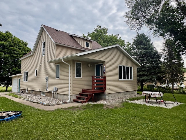 301 Legion Field Rd, Marshall, MN 56258 - rear view of house featuring a lawn, a shingled roof, a garage, and a patio area