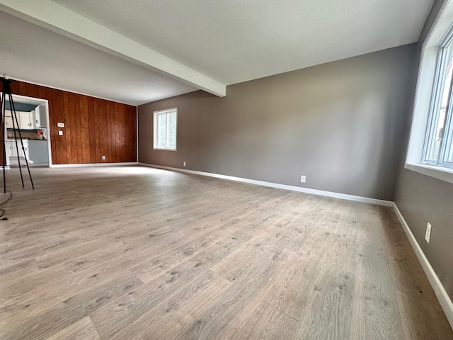 301 Legion Field Rd, Marshall, MN 56258 - unfurnished living room with beam ceiling, wood finished floors, baseboards, and wooden walls