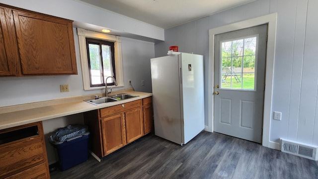 229 2nd Ave, Wanamingo, MN 55983 - kitchen featuring freestanding refrigerator, a sink, dark wood-type flooring, brown cabinets, and light countertops