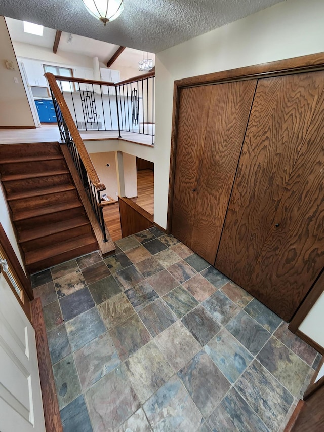 1180 Hathaway Ln NE, Fridley, MN 55432 - stairway featuring stone tile floors, a textured ceiling, and beam ceiling