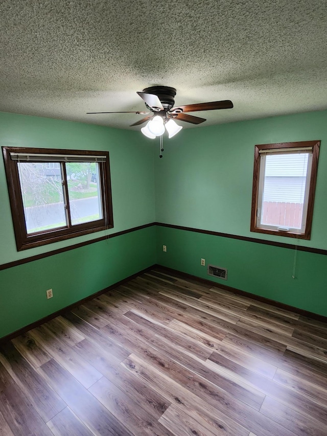 1180 Hathaway Ln NE, Fridley, MN 55432 - unfurnished room featuring healthy amount of natural light, a textured ceiling, a ceiling fan, and wood finished floors