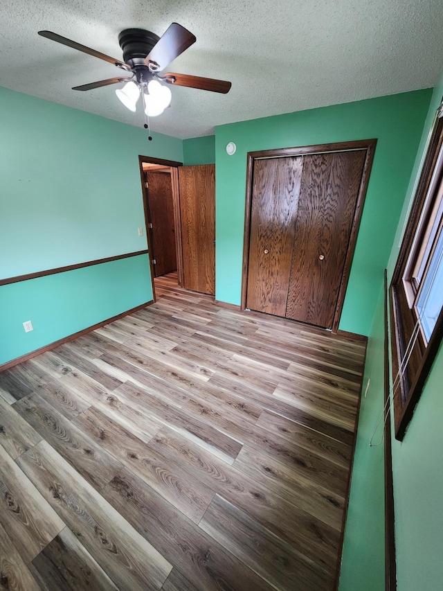 1180 Hathaway Ln NE, Fridley, MN 55432 - unfurnished bedroom featuring wood finished floors, a textured ceiling, a ceiling fan, and a closet