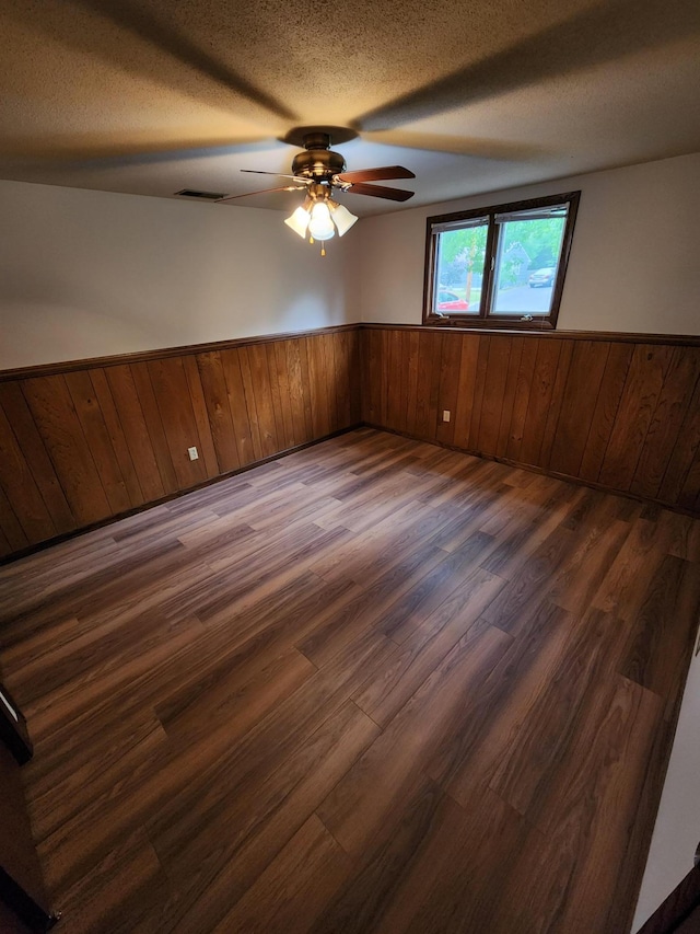 1180 Hathaway Ln NE, Fridley, MN 55432 - unfurnished room with wainscoting, dark wood-style flooring, wooden walls, a ceiling fan, and a textured ceiling
