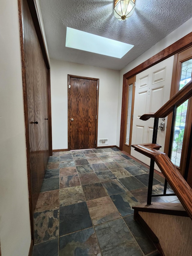 1180 Hathaway Ln NE, Fridley, MN 55432 - foyer entrance with a skylight, stone tile floors, a textured ceiling, and baseboards