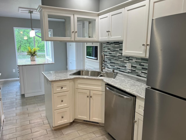 6563 Parkview Cir, Baxter, MN 56425 - kitchen with stainless steel appliances, a sink, a peninsula, decorative backsplash, and white cabinetry