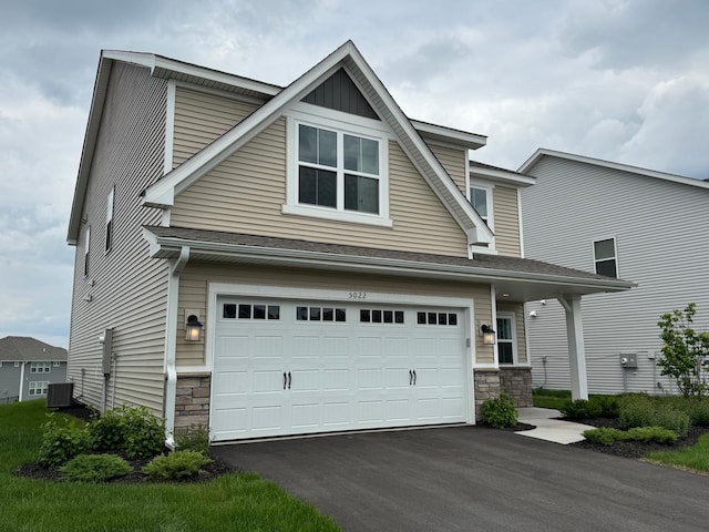 5022 Useppa Trl, Woodbury, MN 55129 - view of front of house featuring stone siding, an attached garage, asphalt driveway, and cooling unit