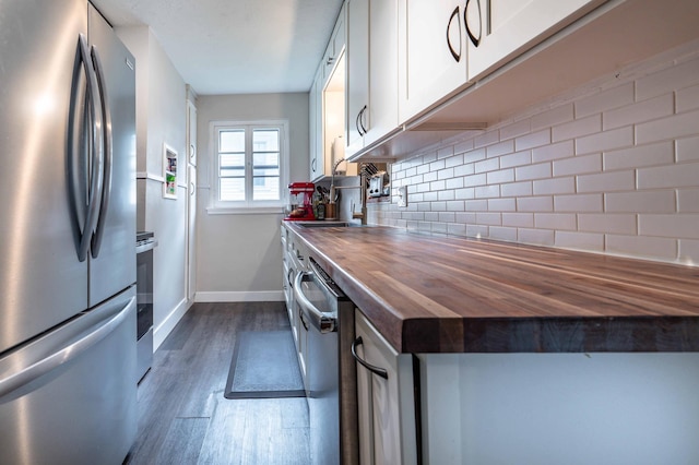 327 Channing Ave, Fergus Falls, MN 56537 - kitchen featuring stainless steel appliances, wood counters, dark wood-style flooring, decorative backsplash, and baseboards