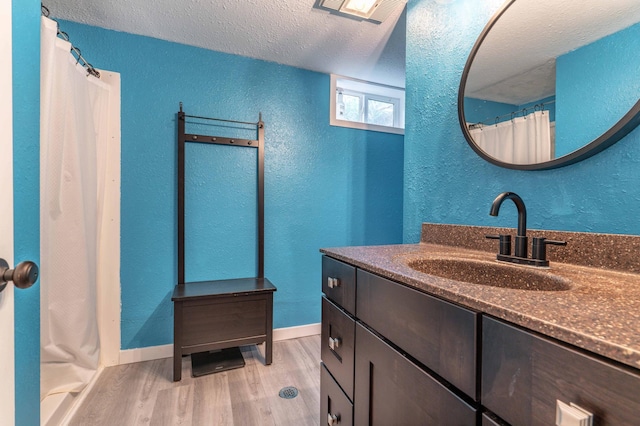 327 Channing Ave, Fergus Falls, MN 56537 - bathroom featuring a textured wall, a textured ceiling, vanity, wood finished floors, and baseboards