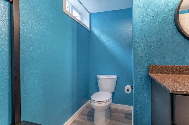 327 Channing Ave, Fergus Falls, MN 56537 - half bath with a textured wall, toilet, wood finished floors, vanity, and baseboards
