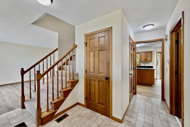 7158 Deerwood Ln N, Maple Grove, MN 55369 - staircase featuring a textured ceiling and tile patterned floors
