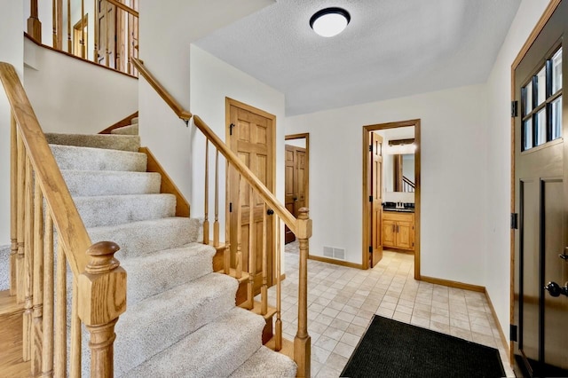 7158 Deerwood Ln N, Maple Grove, MN 55369 - foyer entrance featuring a textured ceiling, stairs, and light tile patterned flooring