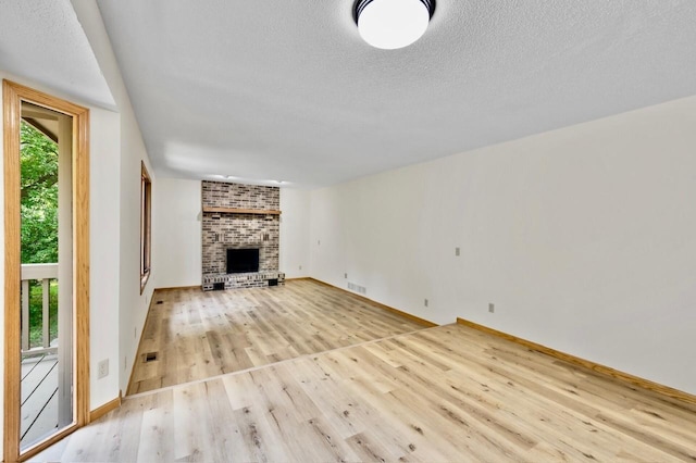 7158 Deerwood Ln N, Maple Grove, MN 55369 - unfurnished living room with light wood-style floors, a textured ceiling, and a fireplace