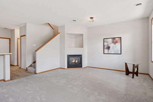 10612 172nd Ln NW, Elk River, MN 55330 - unfurnished living room with light colored carpet, stairway, baseboards, and a glass covered fireplace